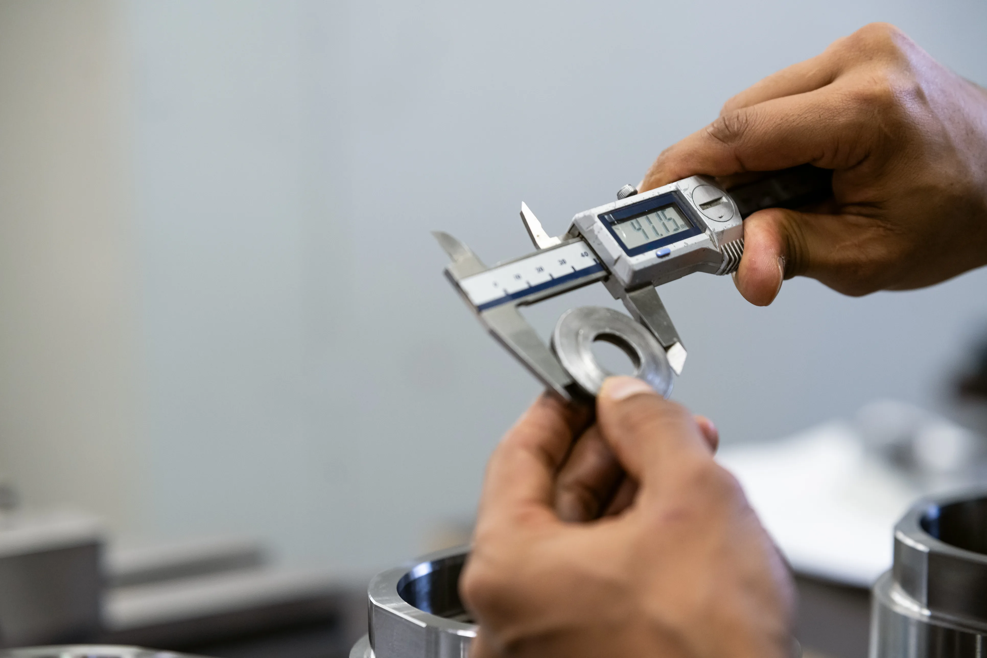 Digital callipers measuring a precision machined hydraulic component — dimensional verification